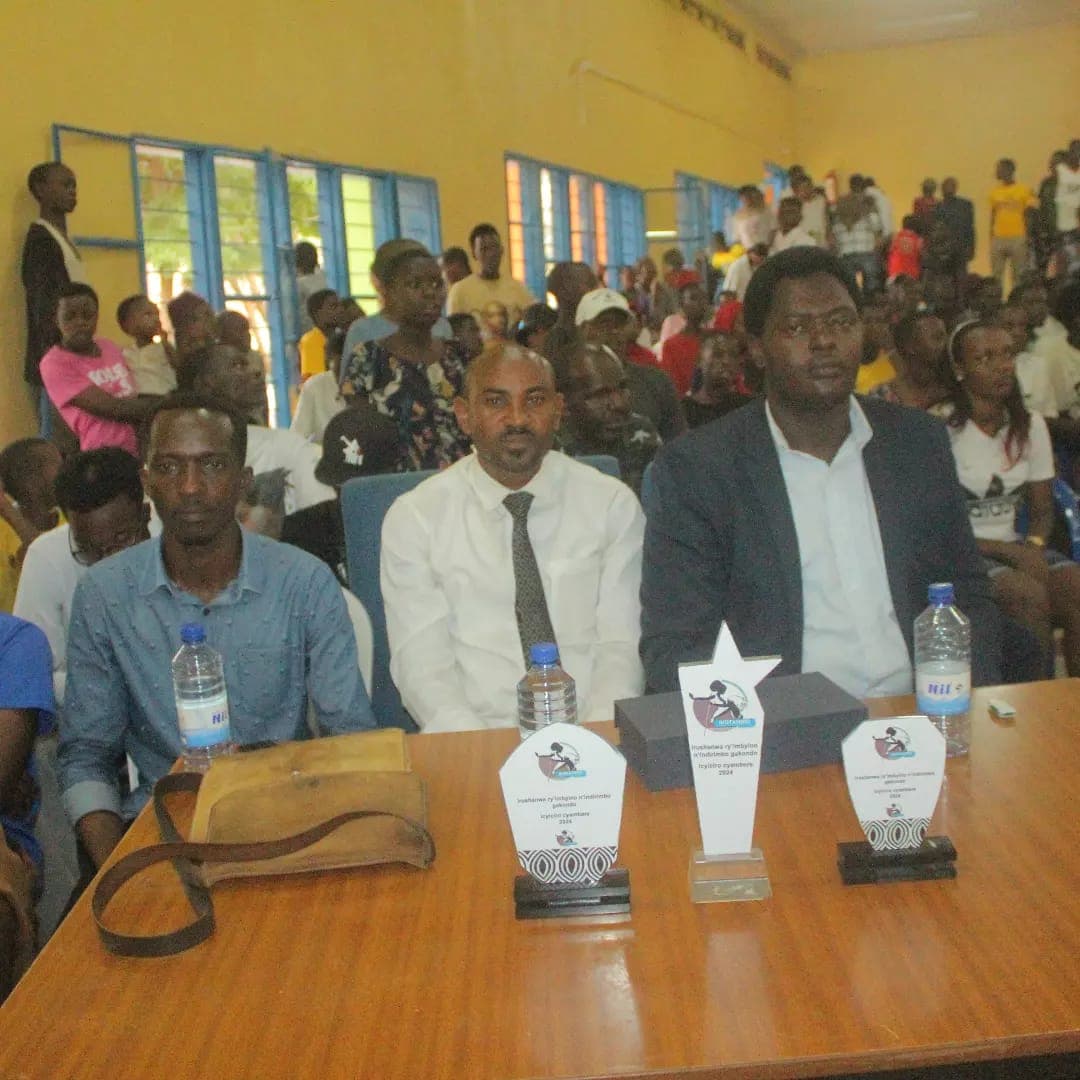 RFM jury committee and leadership seated with official youth music competition trophies in community hall